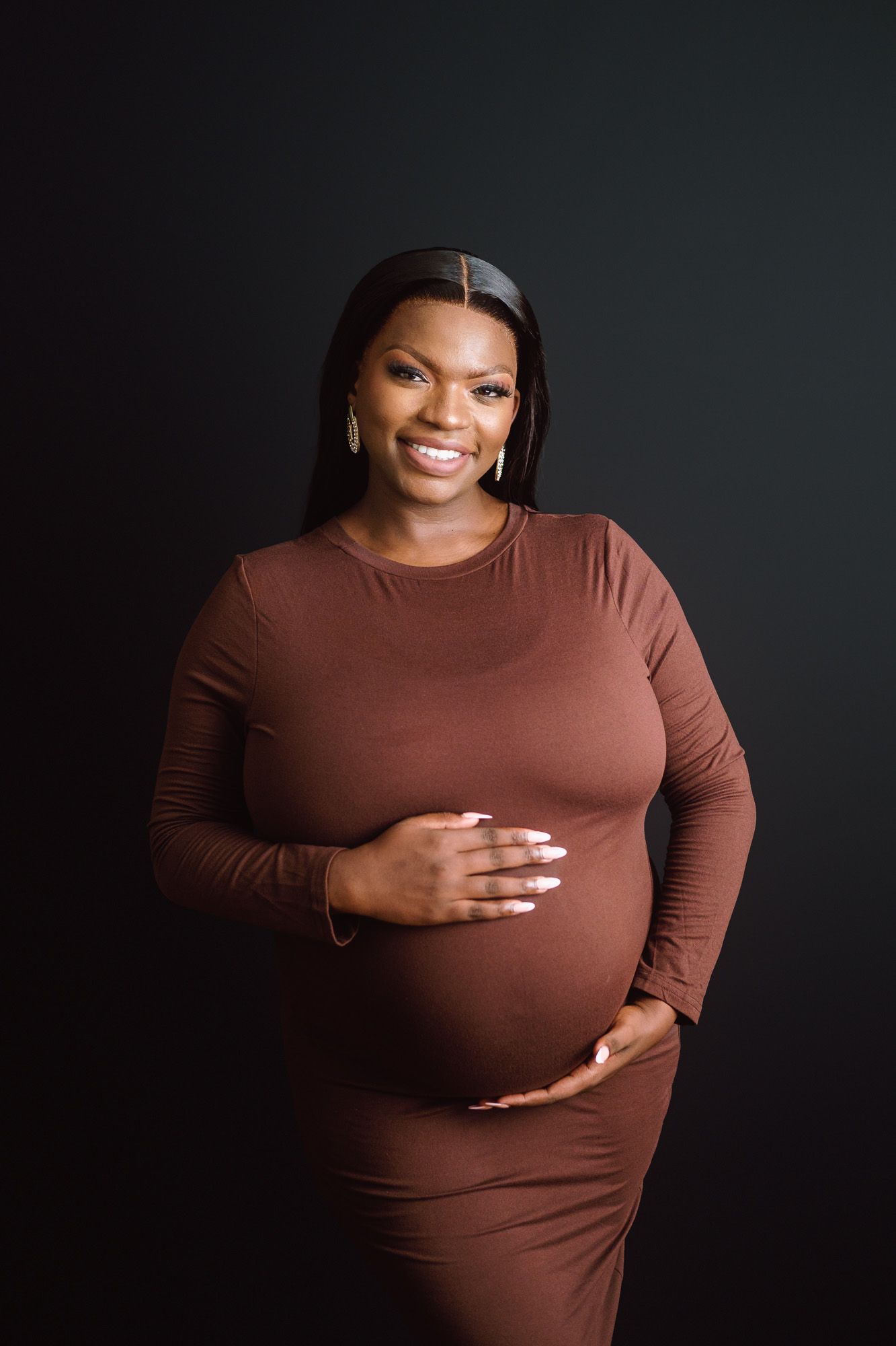 Pregnant woman holding her baby bump during a timeless studio maternity photography session
