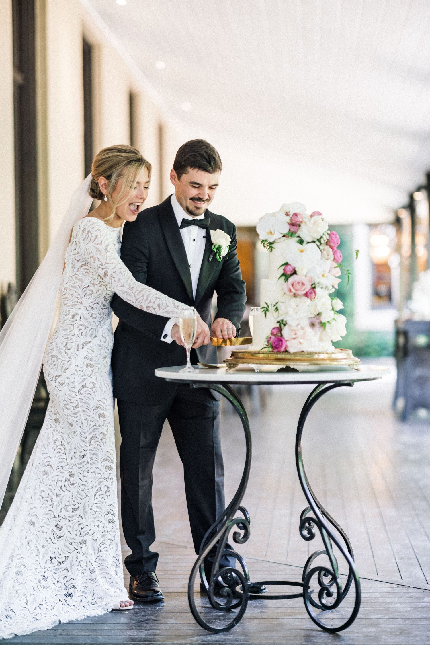 Bride and groom smiling as they cut their floral wedding cake at Jaspers Berry during their wedding reception.