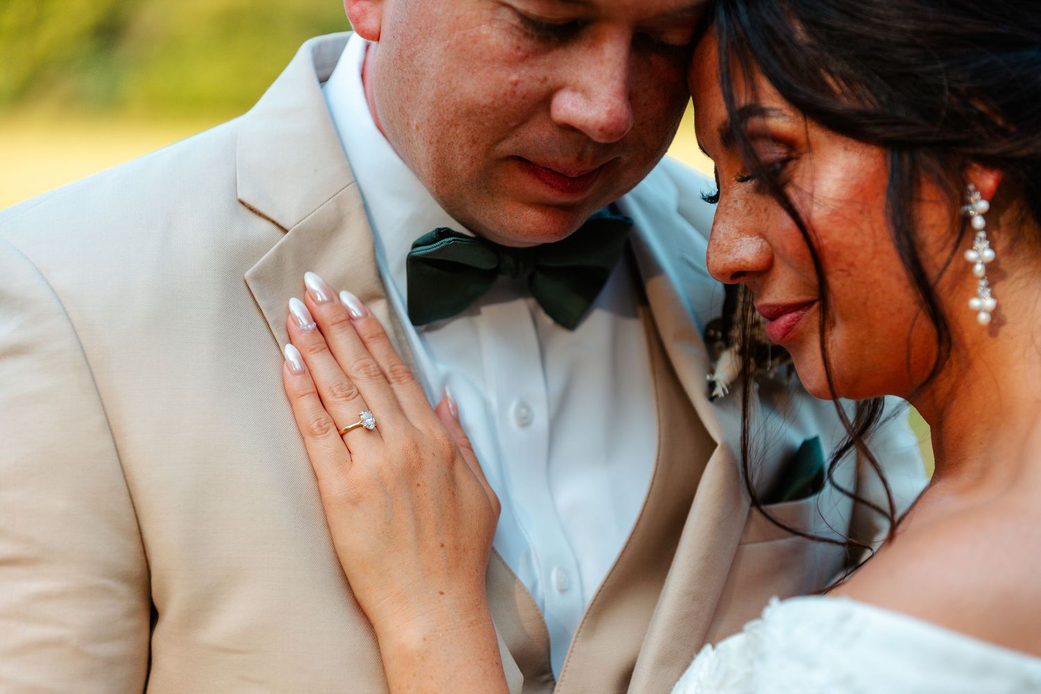 Close-up of bride and groom sharing an intimate moment, showcasing her diamond engagement ring.