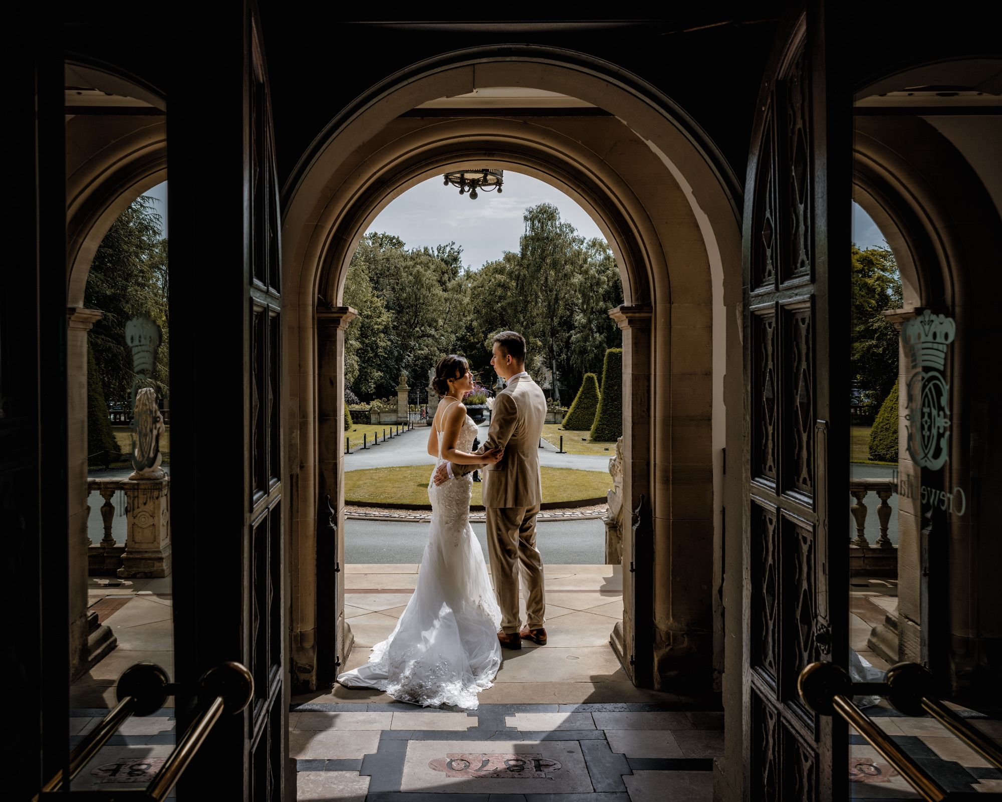 Bride and groom share a romantic moment framed by elegant arched doors at a stunning outdoor wedding venue.