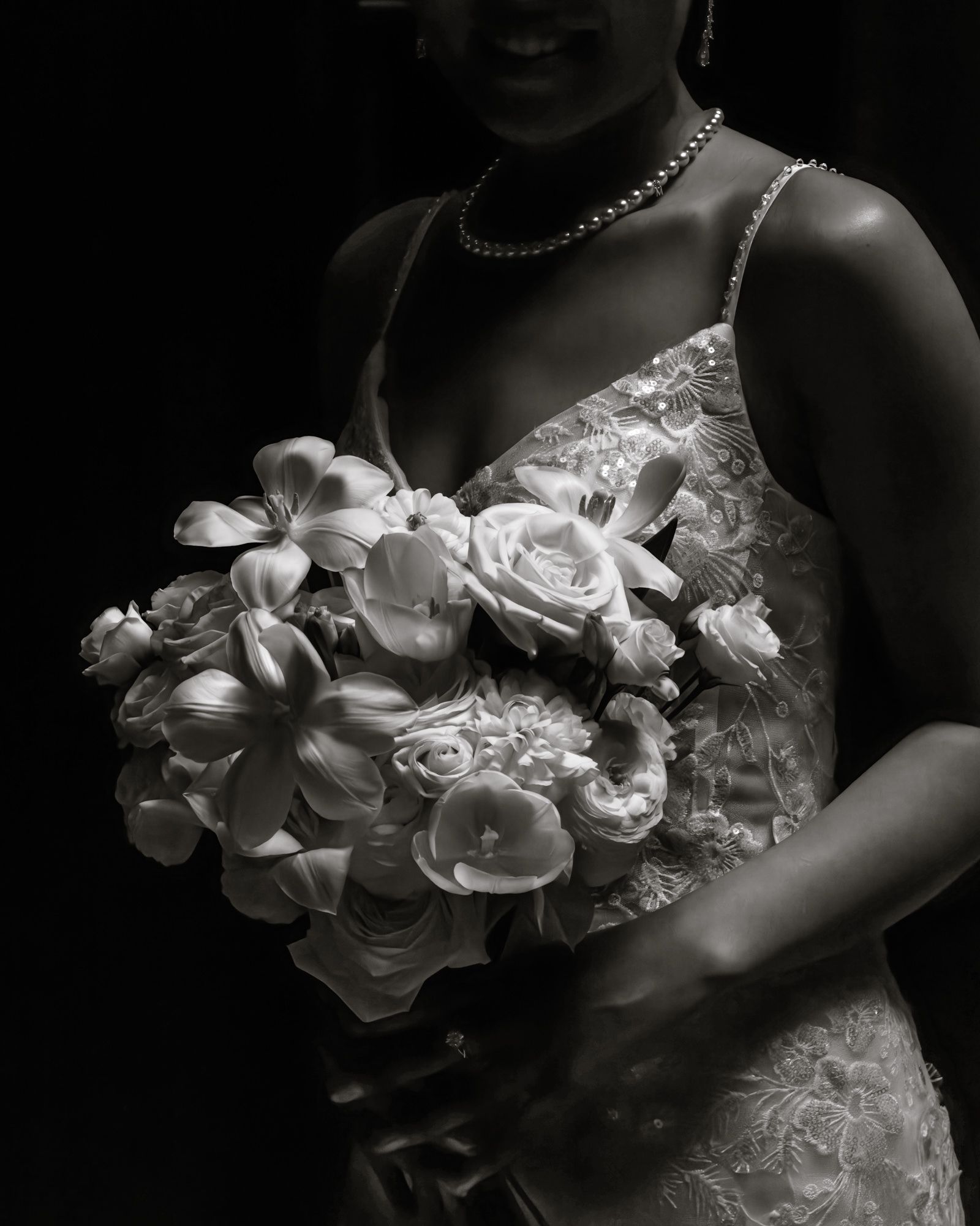 Bride holding a lush bouquet of roses and flowers in a black and white wedding photo.