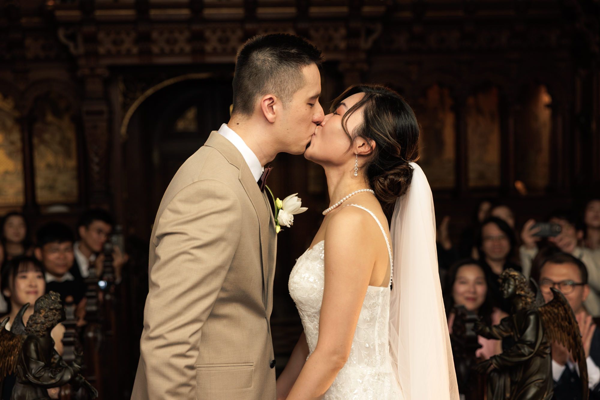 Bride and groom share their first kiss at the altar during a wedding ceremony in an elegant venue.