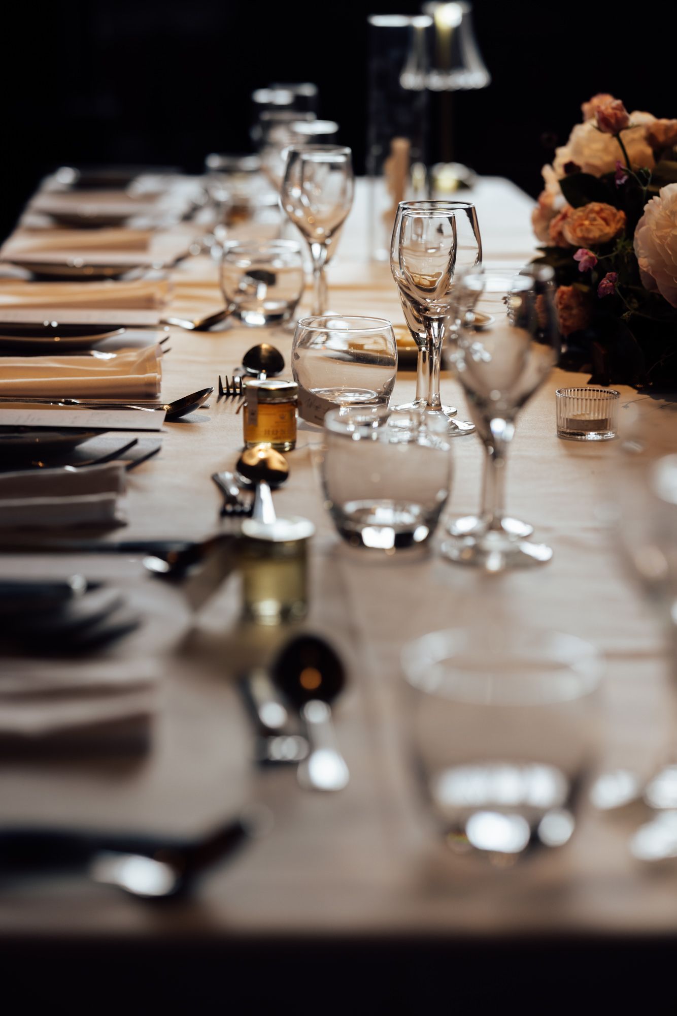 Elegant banquet table set with crystal glasses, silverware, linen napkins, and floral centerpiece for a formal dinner event.