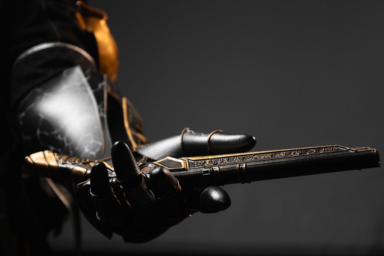 Armored gauntlet holding an ornate gold and black decorated antique pistol against dark background.
