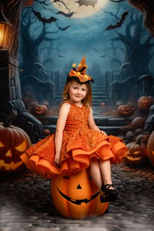A spooky Halloween scene with jack-o'-lanterns, bats, and an orange dress against a misty forest backdrop.