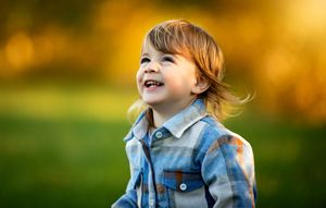 A child in denim plays outdoors during golden hour autumn sunlight, creating a joyful and energetic scene.