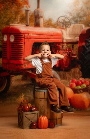 Fall harvest scene with vintage red tractor, wooden barrels, decorative pumpkins and autumn foliage in studio setting.