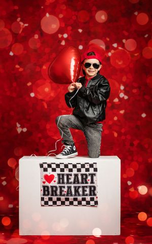 Valentine themed photo with child in leather jacket posing with heart balloon on white cube prop.