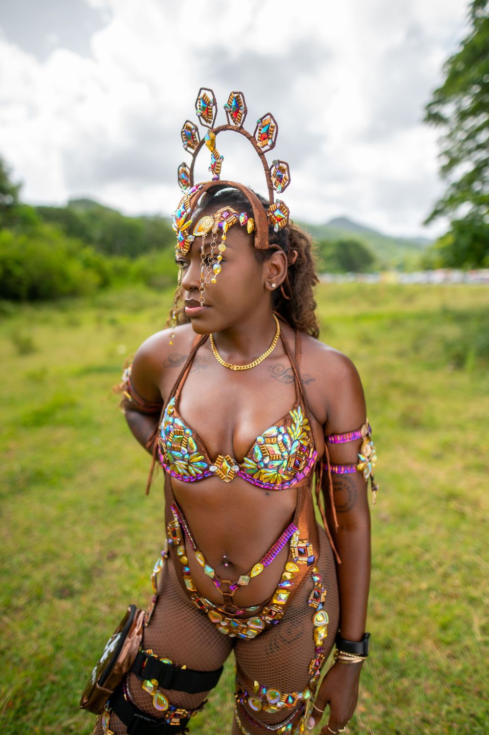 Woman in colorful carnival costume with decorative headpiece poses outdoors at a Caribbean festival.