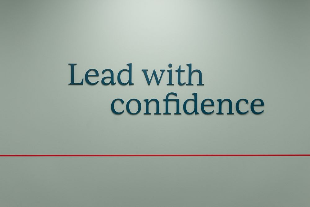 Wall displaying motivational text Lead with confidence in teal letters above a red line on a light green background.