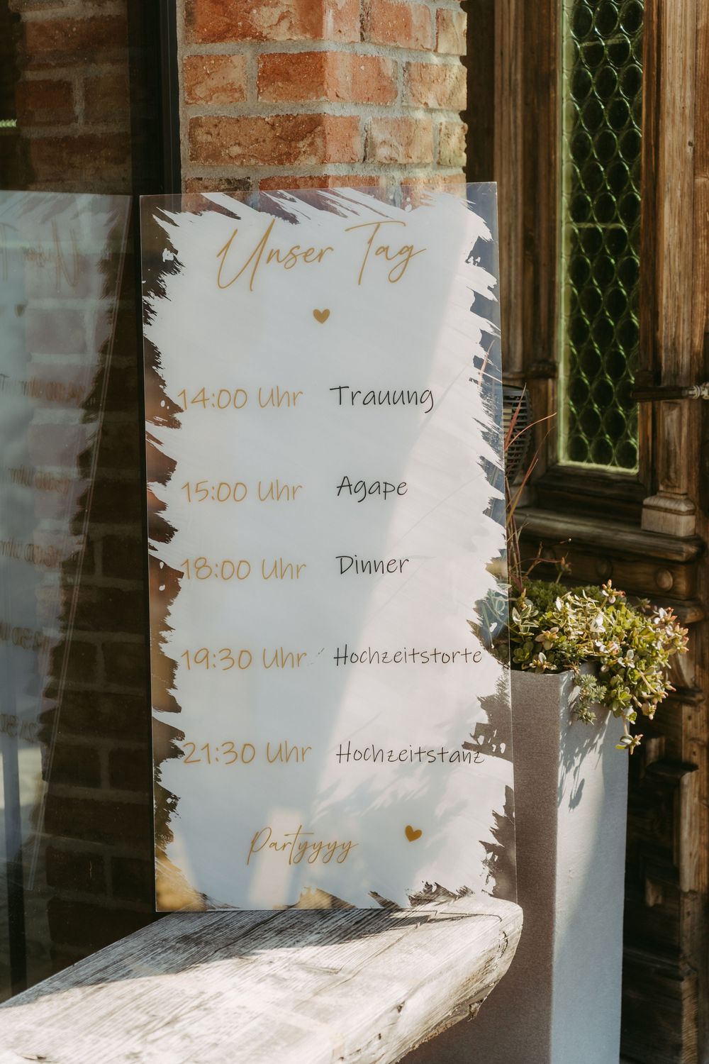 German wedding day schedule sign reading Unser Tag listing ceremony dinner and party times.