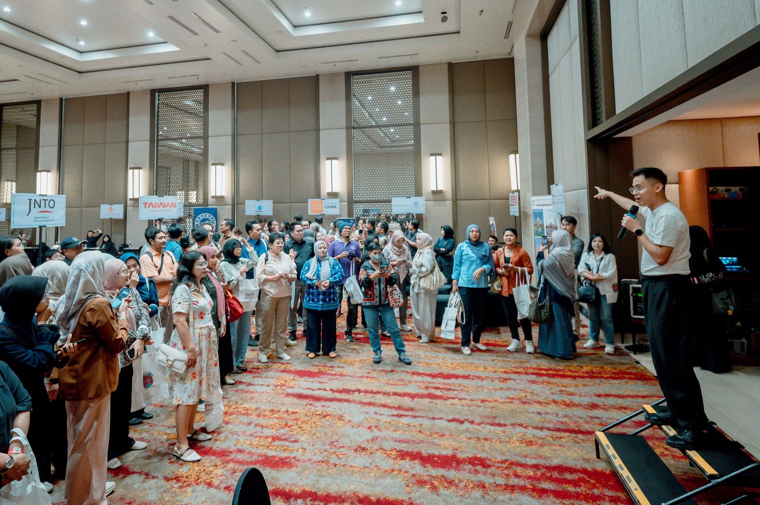 Crowded conference hall with attendees networking at exhibition booths during a professional business event.