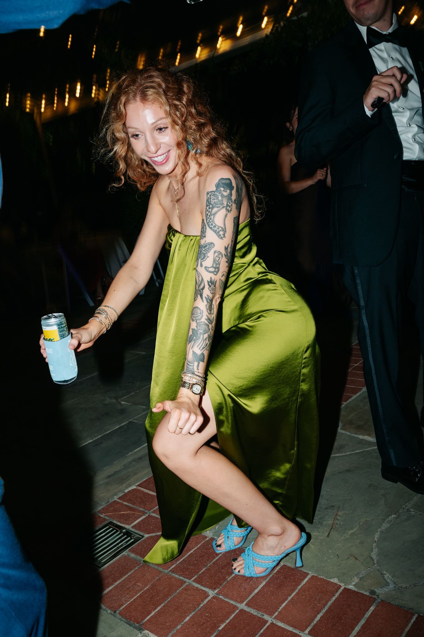 A female wedding guest in a green dress dancing during wedding reception.