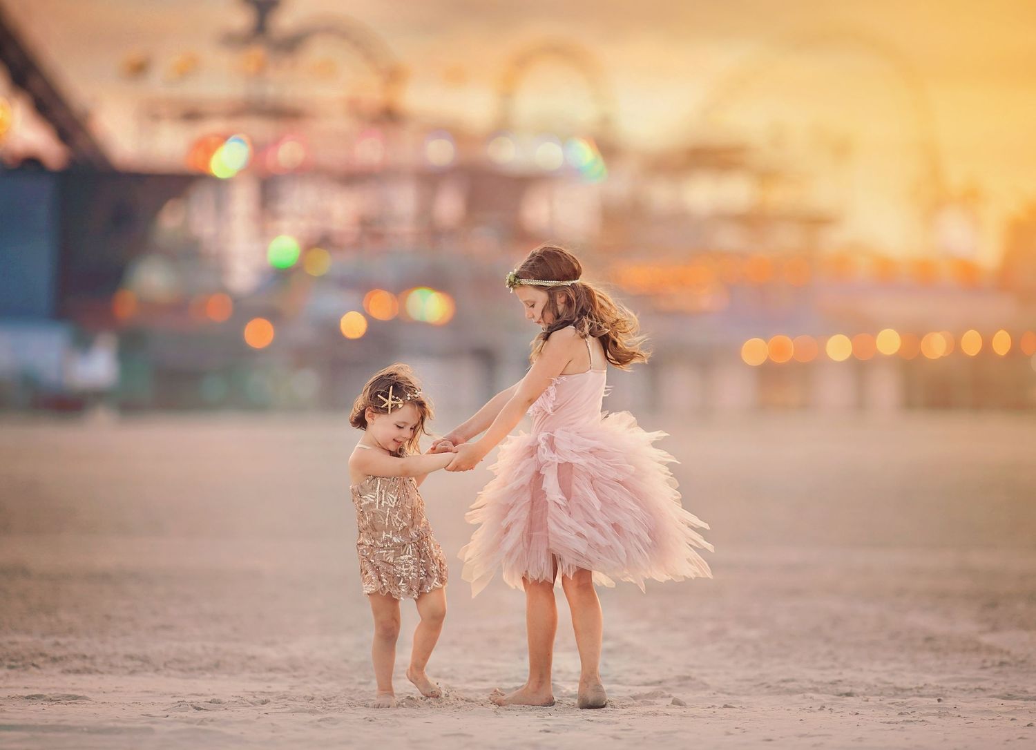 Two sisters posing on the beach in Wildwood, New Jersey, with a boardwalk roller coaster in the background.