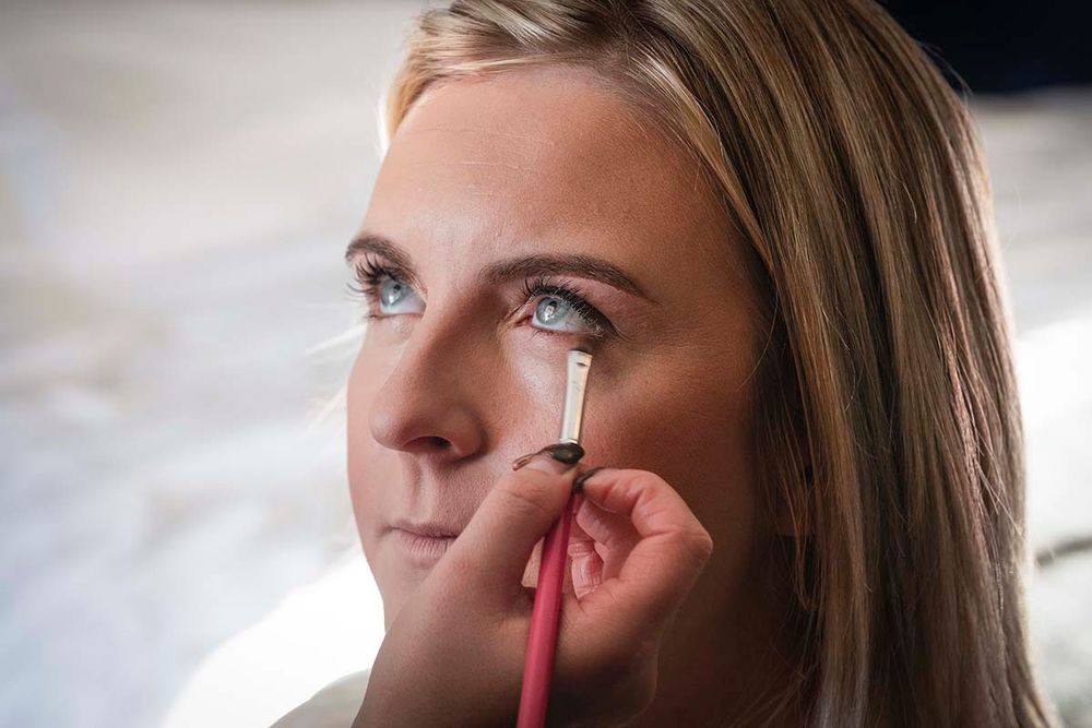 Professional makeup artist applying eye makeup to Abbie at Hetland Hall wedding venue near Annan