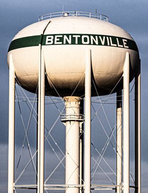 Bentonville water tower with green stripe and bold lettering against a cloudy sky.