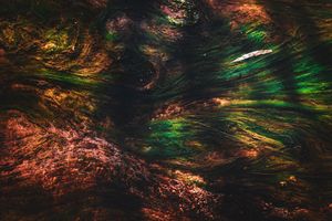 Abstract swirling texture with vibrant green, red, and brown tones creating a dynamic, organic pattern.