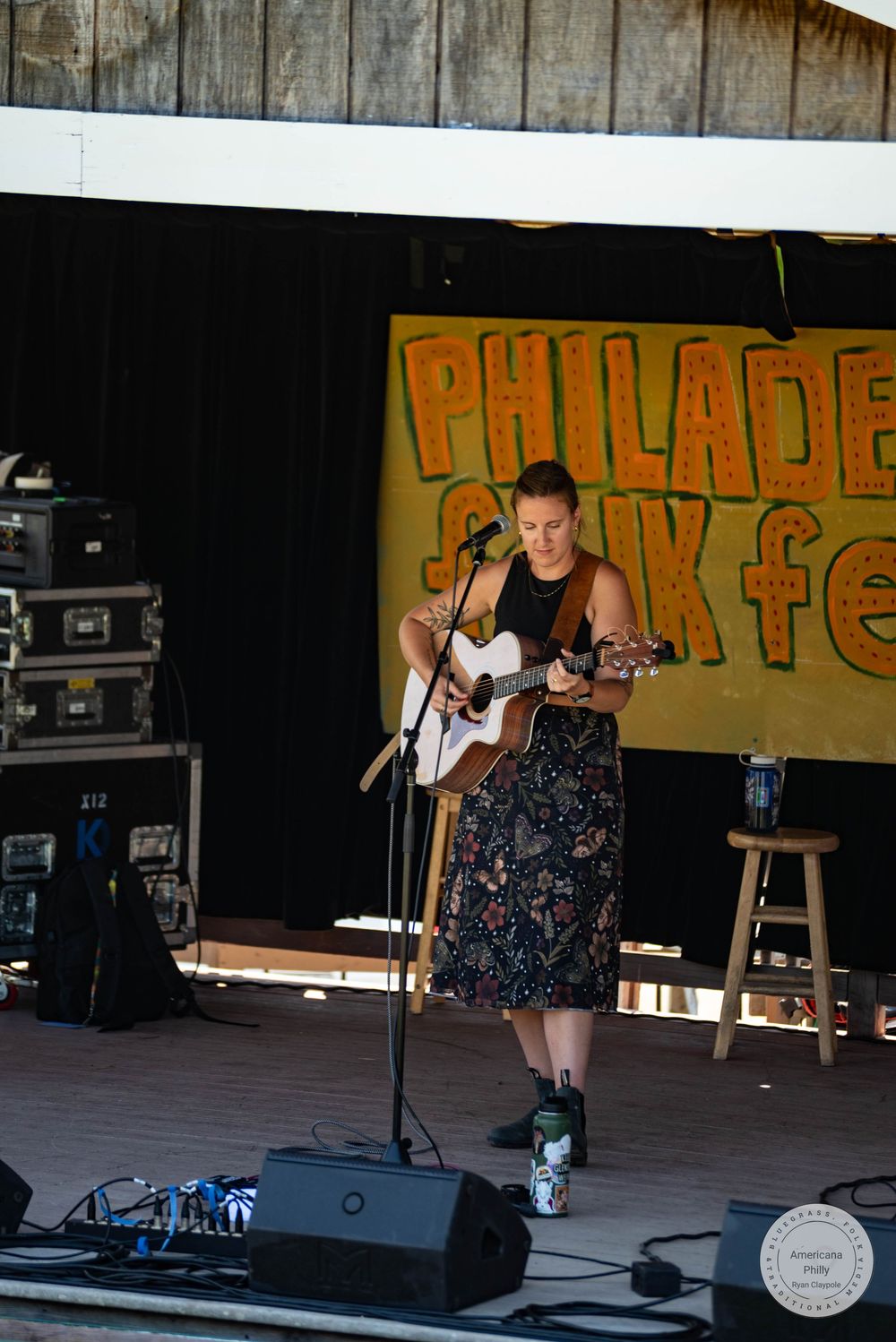 Female guitarist performs on stage at Philadelphia Folk Festival in floral skirt.