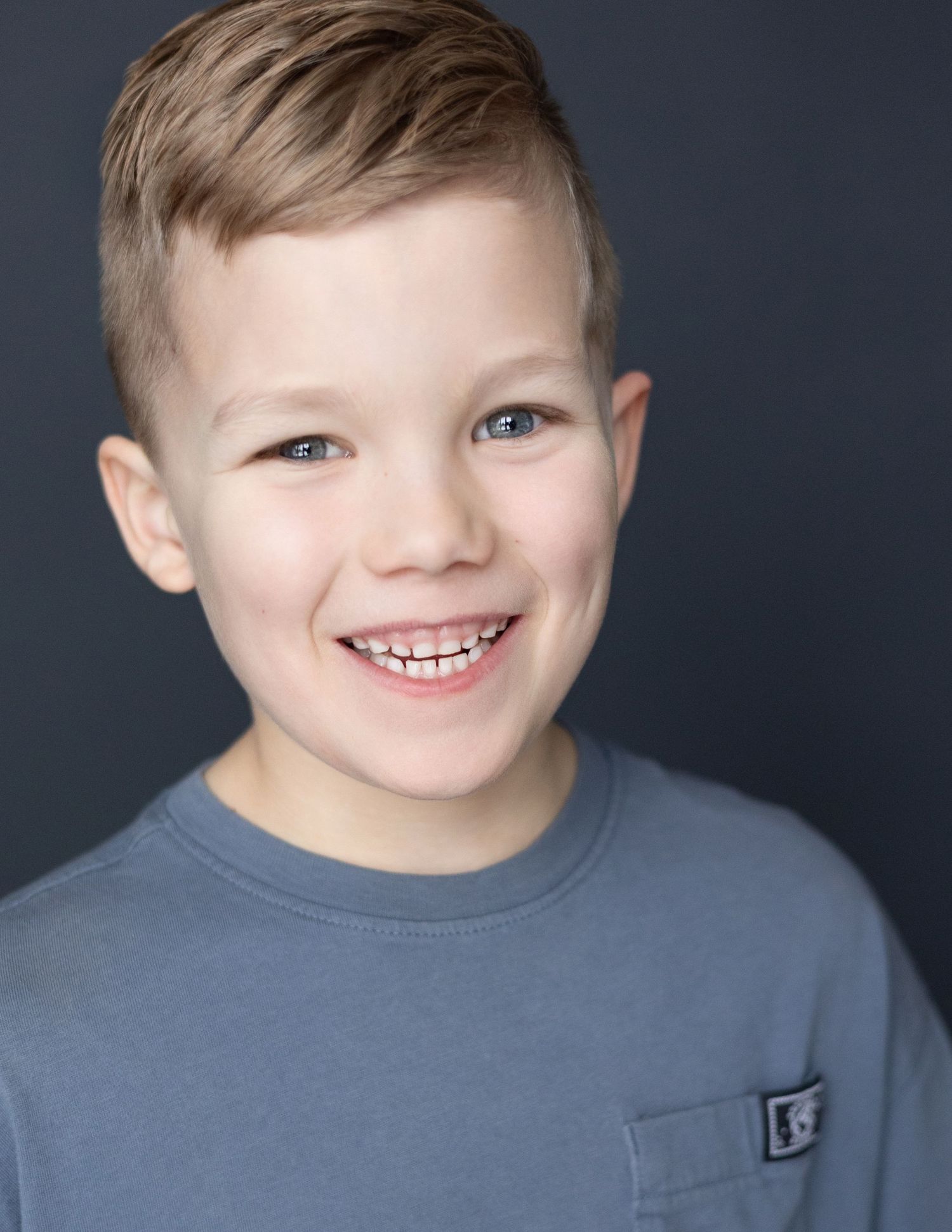 Child actor headshot with natural smile on grey backdrop