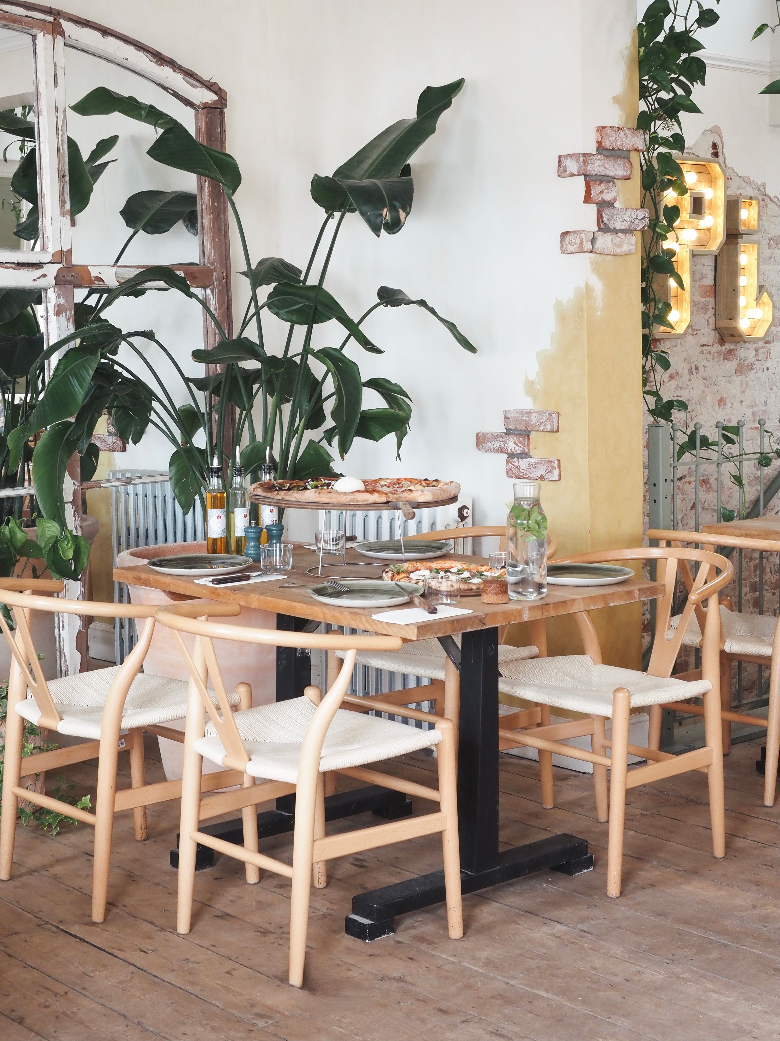 Stylish dining area featuring wooden chairs, indoor plants, and exposed brick wall details.