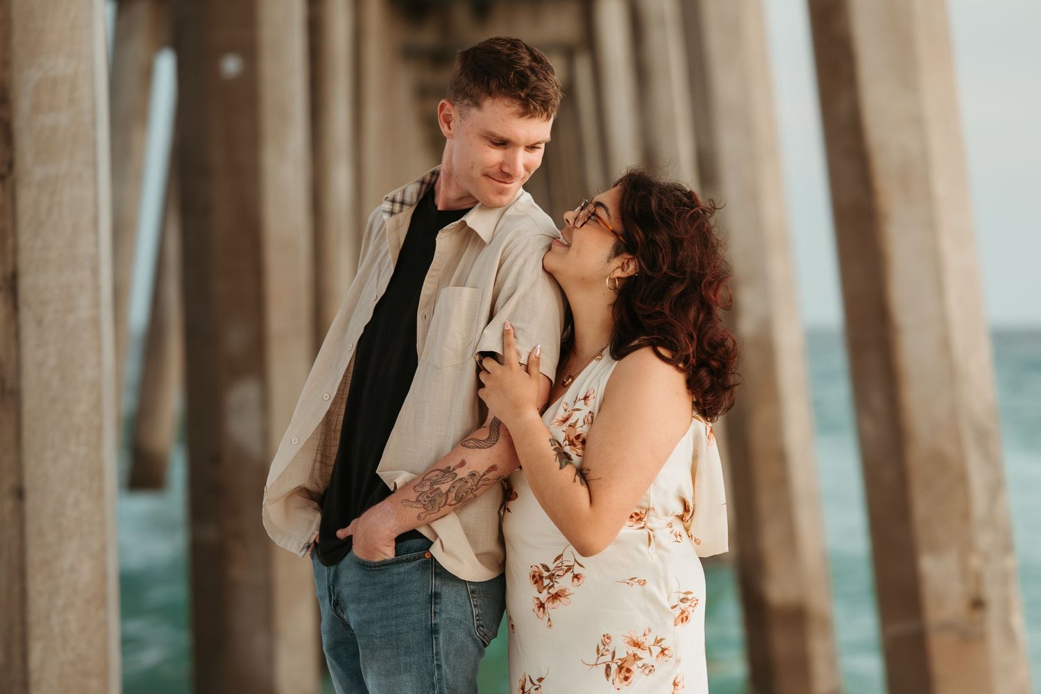 Couple smiling together beneath the pier during a Pensacola Beach photography session