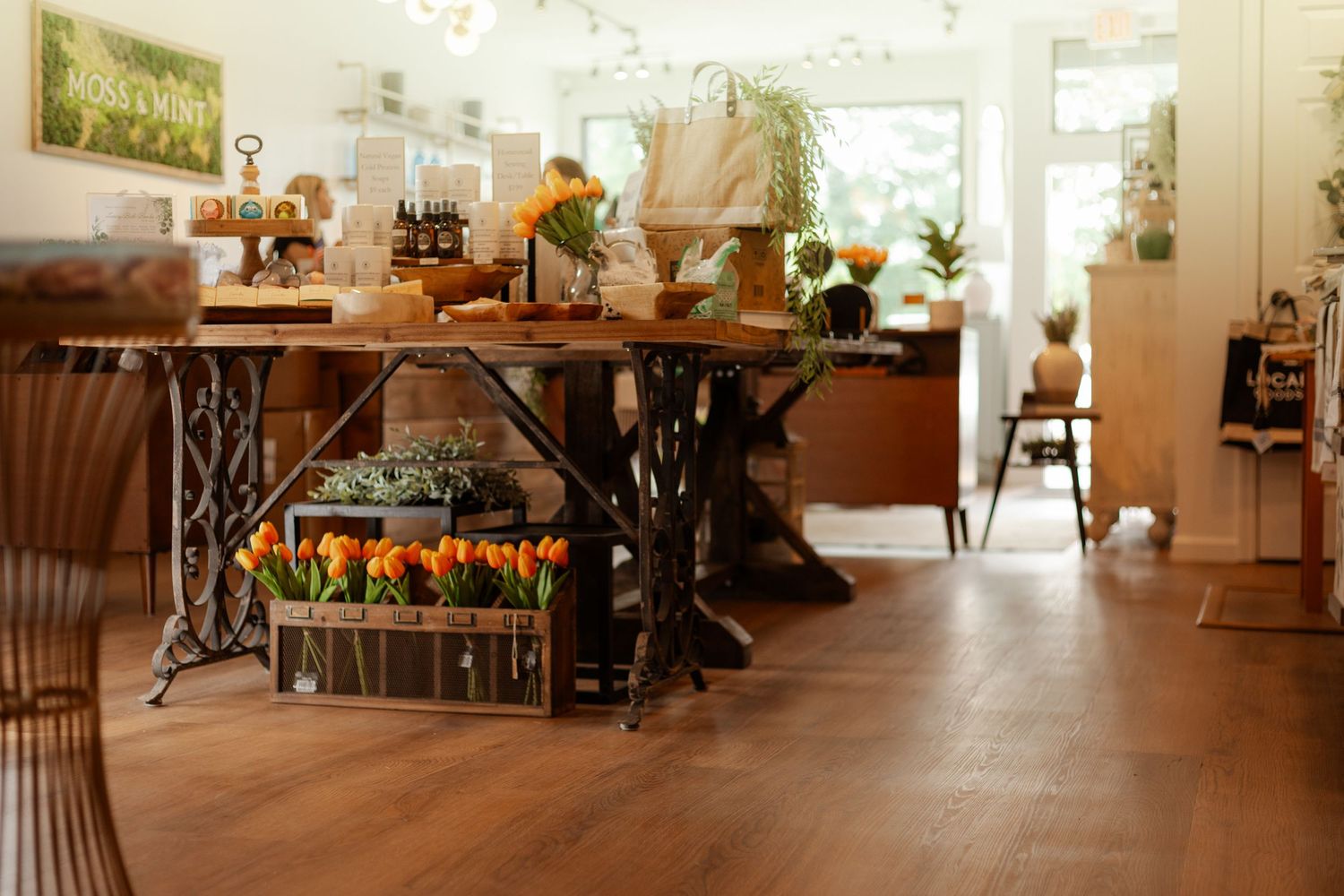 Cozy flower shop interior with tulips, plants, and rustic wooden tables on warm hardwood floors.