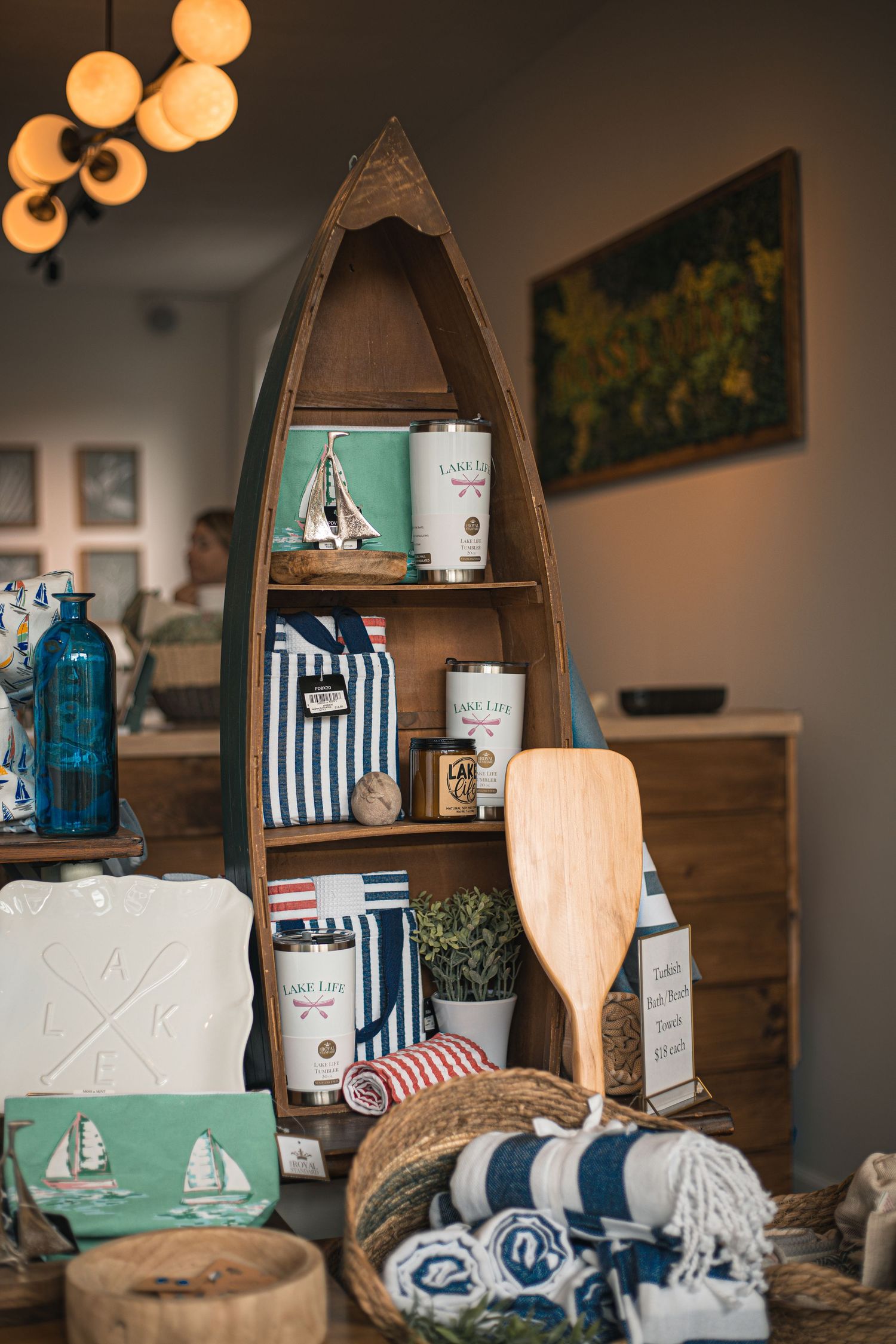 Nautical-themed gift shop display with boat shelf, oar, striped bags, and lake-inspired decor items.