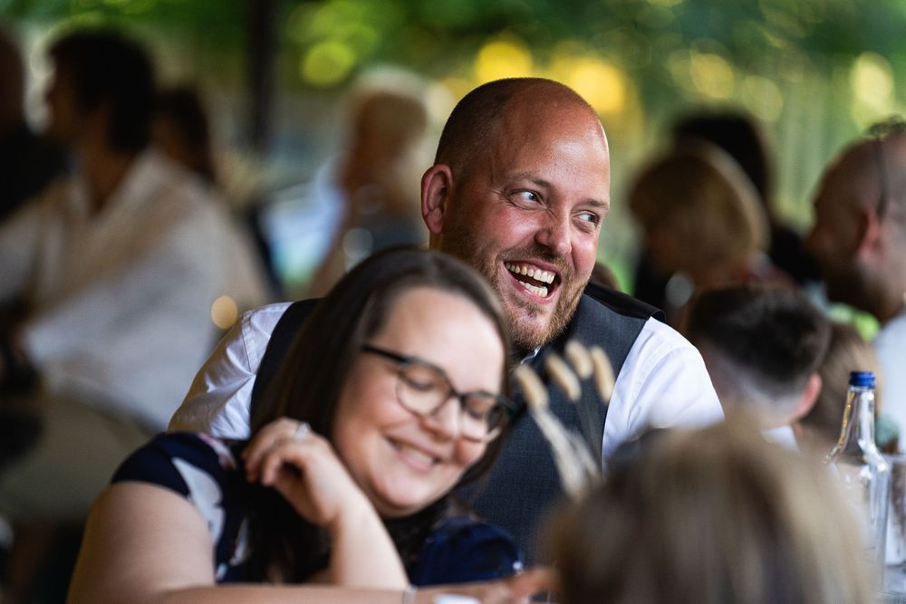 People laugh and enjoy themselves during a social gathering with a bright natural background.