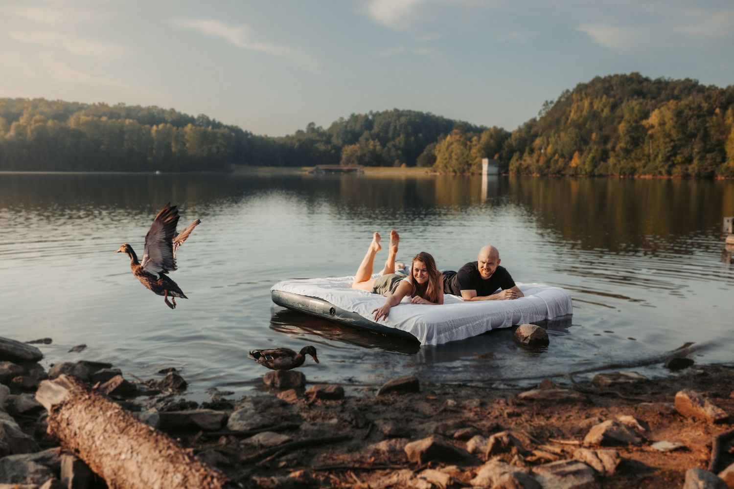 Panoramic view of people enjoying a lake with mountains and rocks in background.