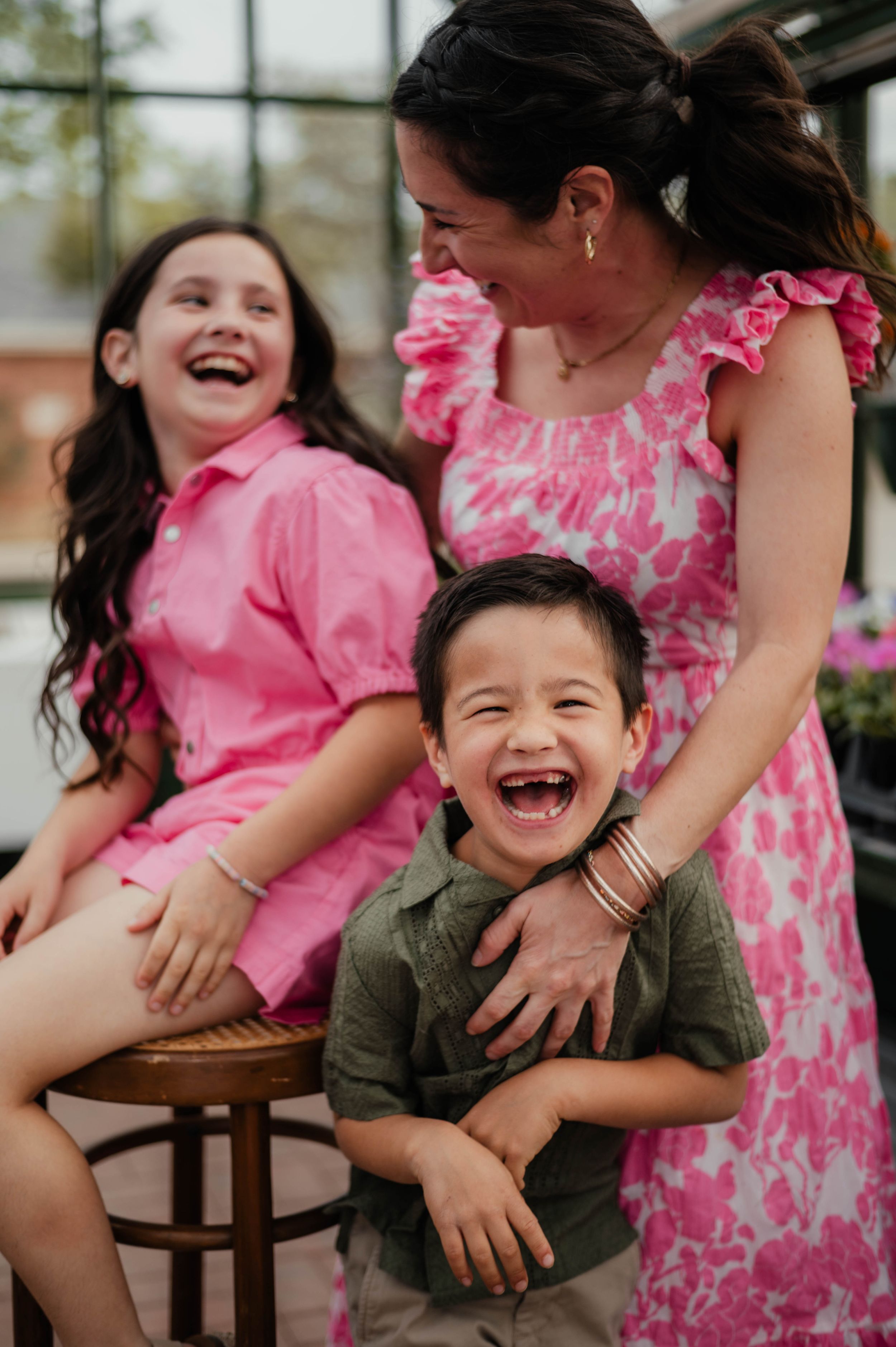 A joyful family moment captured in a greenhouse with pink floral accents.