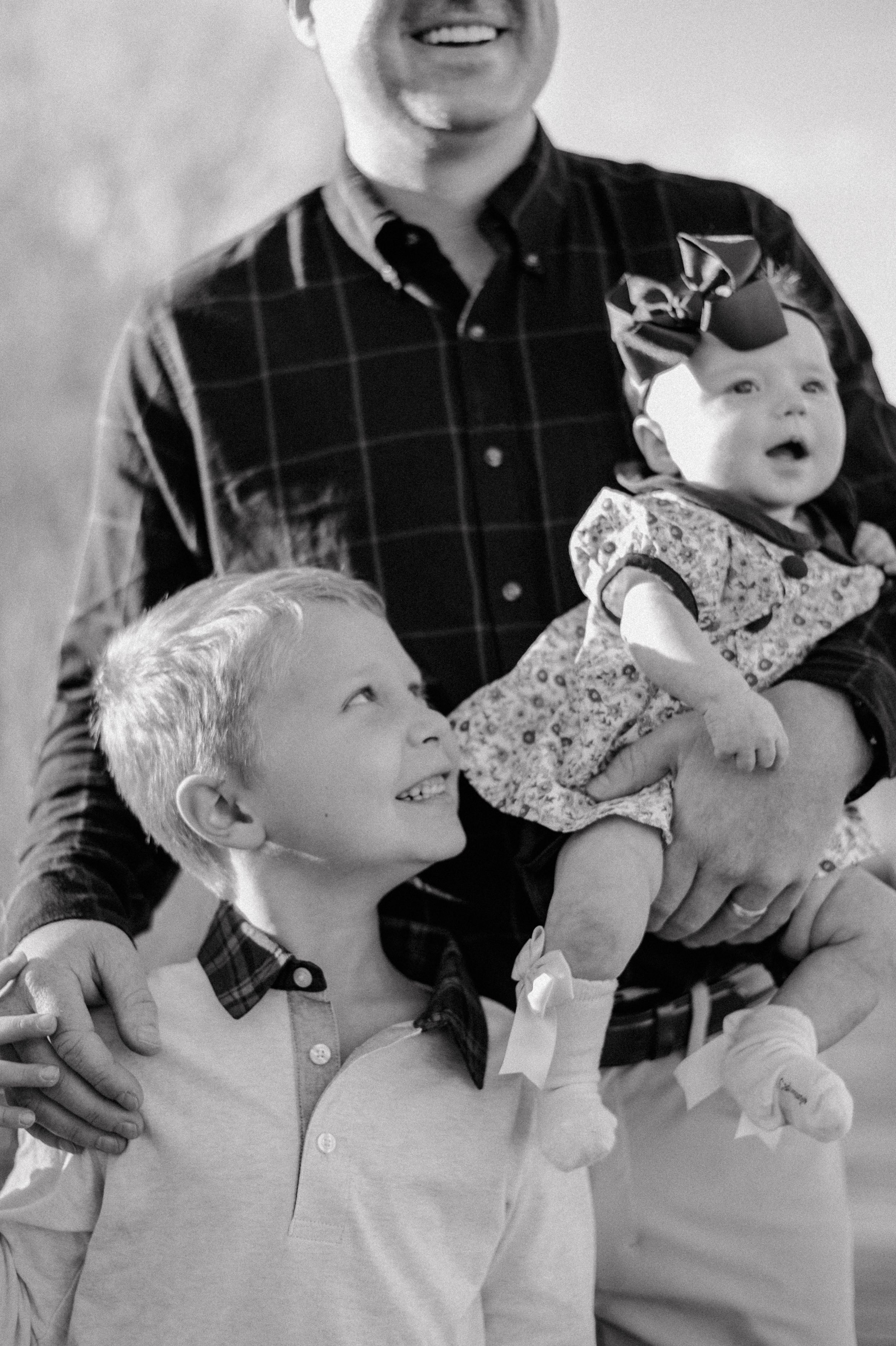 A black and white candid family portrait showing joyful expressions.