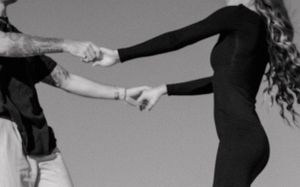 Black and white image showing two people holding hands in an artistic dance pose.