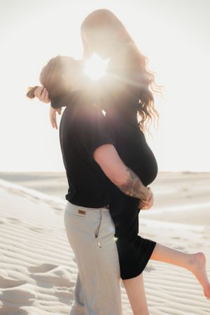 Silhouetted couple embracing on beach during golden sunset.