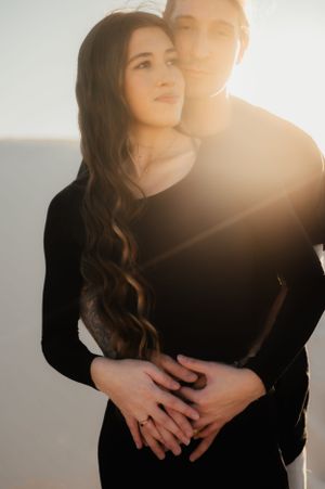 Backlit couple sharing intimate embrace in warm sunlight.