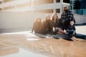 Group sitting together on floor in sunlit building with cheerful expressions.