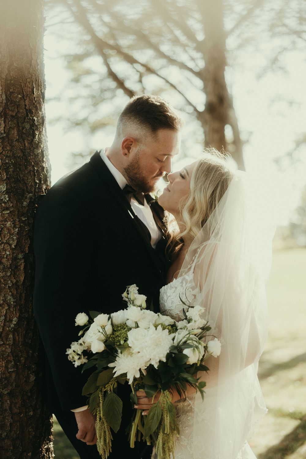 Romantic wedding portraits with couple holding white flowers in dreamy forest setting.