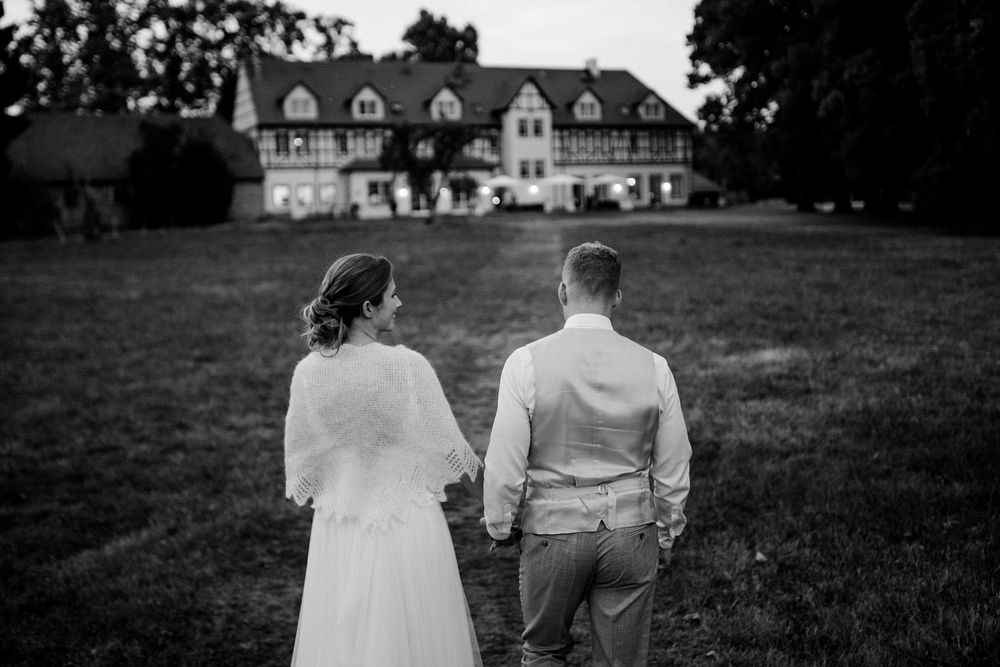 A couple stands hand in hand overlooking a grand country estate house with dormers in a black and white scene.Weiherhof Wächtersbach