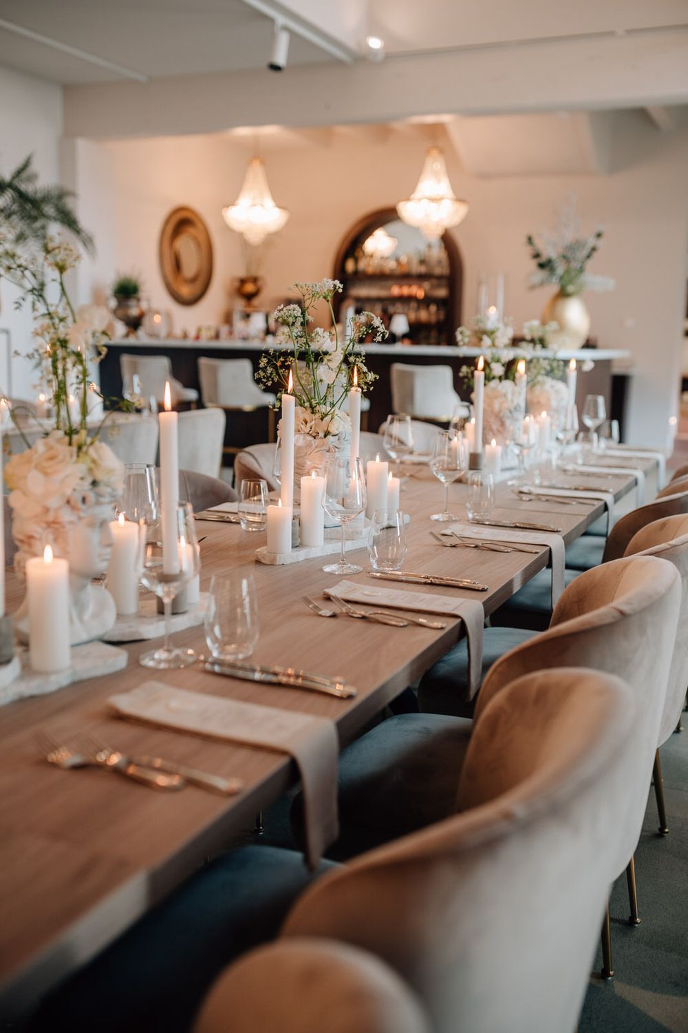 Elegant restaurant table setting with white candles, delicate floral centerpieces, and plush velvet chairs.. la vette ortenberg