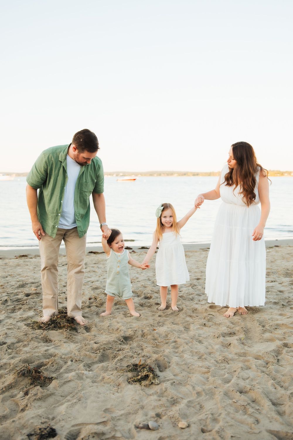 Family of four holding hands on sandy beach. Portsmouth, RI Rhode Island