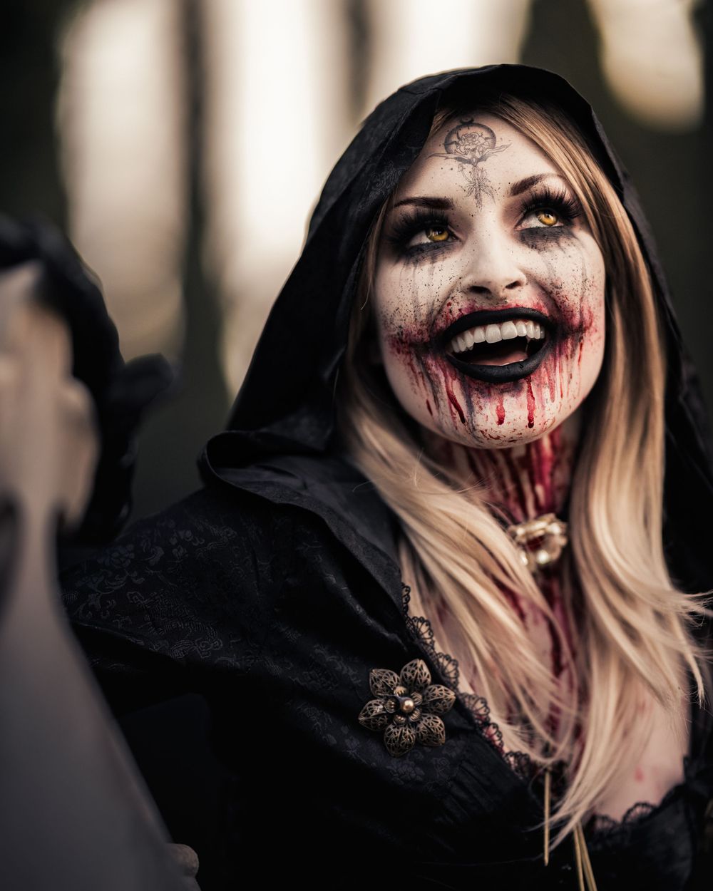 Bela Dimitrescu horror cosplay with bloodstained mouth and clawed hand poses at dusk in a cemetery captured by Chris Cornish Photography.