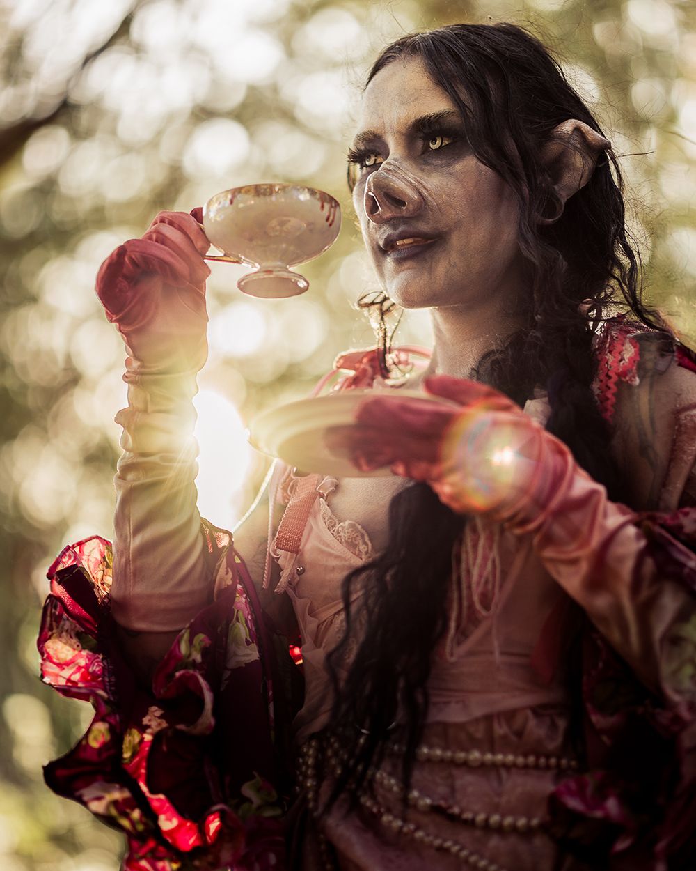 Female horror character in a pig mask sips tea at a table set for a twisted tea party, captured by Chris Cornish Photography.