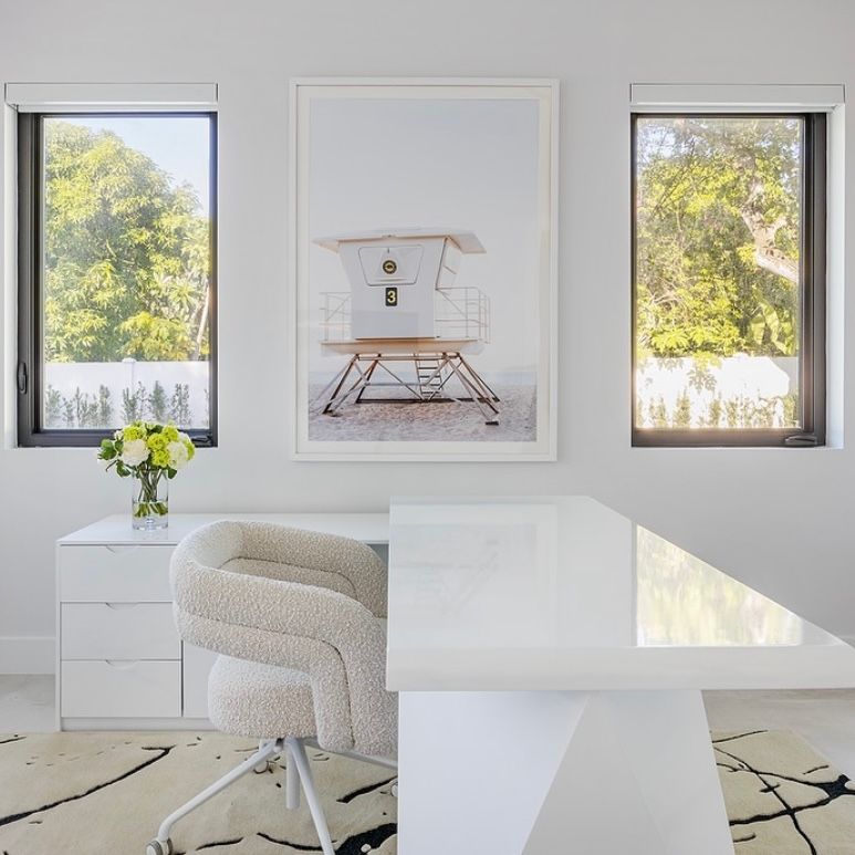A bright modern living room featuring multiple framed art pieces on white walls and clean contemporary furniture.