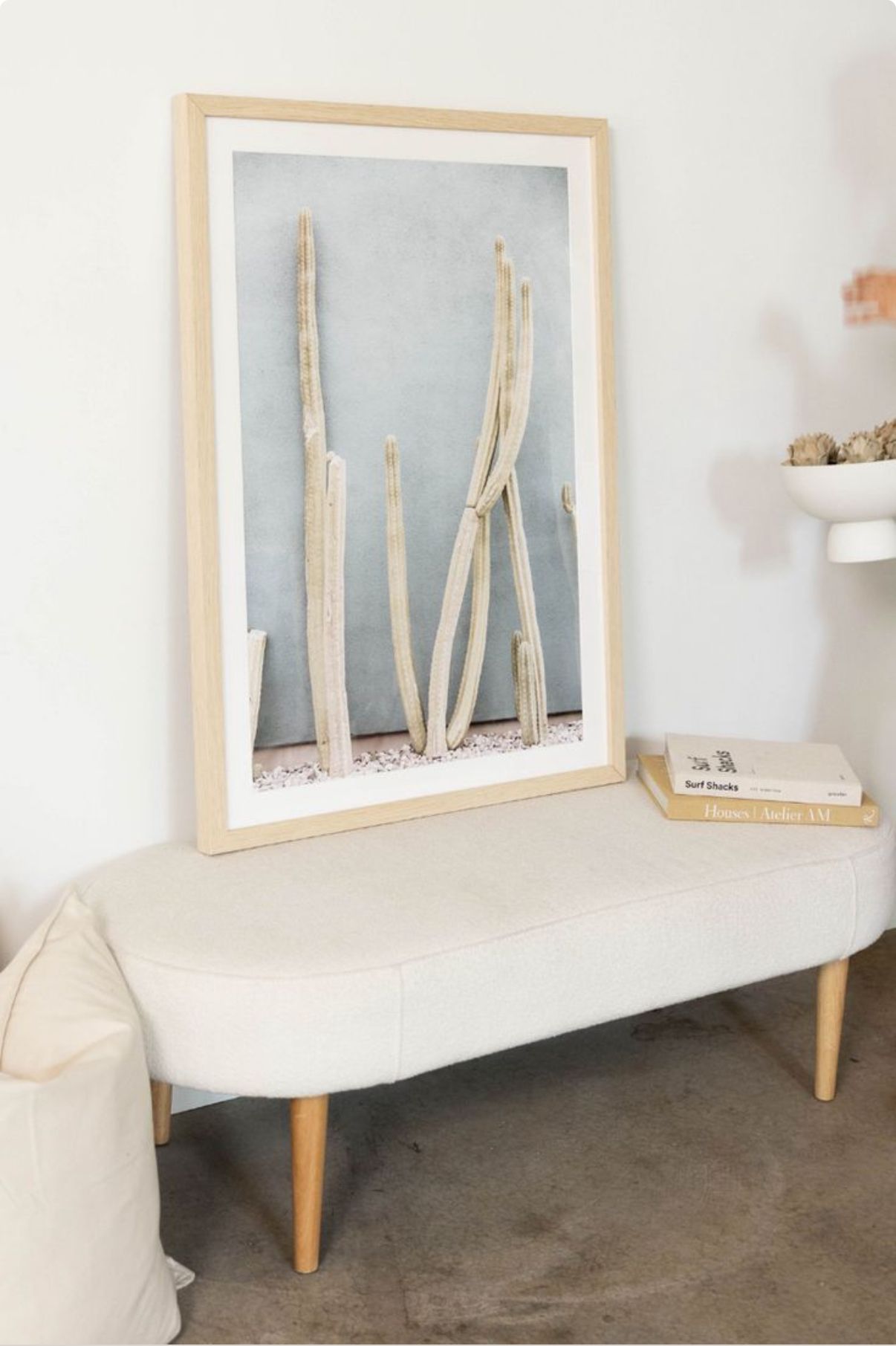 A set of four images showing a minimalist white console table with wooden legs against a wall displaying framed artwork.