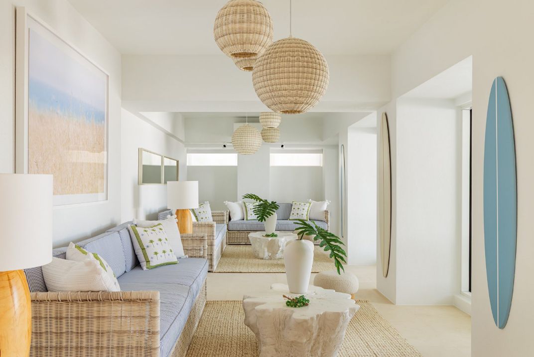 Modern coastal-inspired interior with rattan pendant lights and surfboard decor in an airy white space.