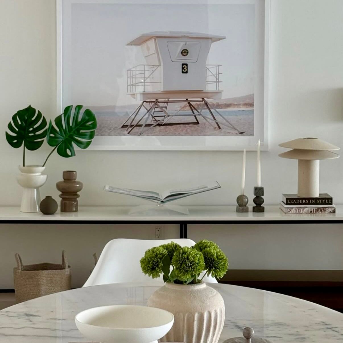 Modern white home decor featuring vases, greenery, and minimalist shelving on a neutral backdrop.