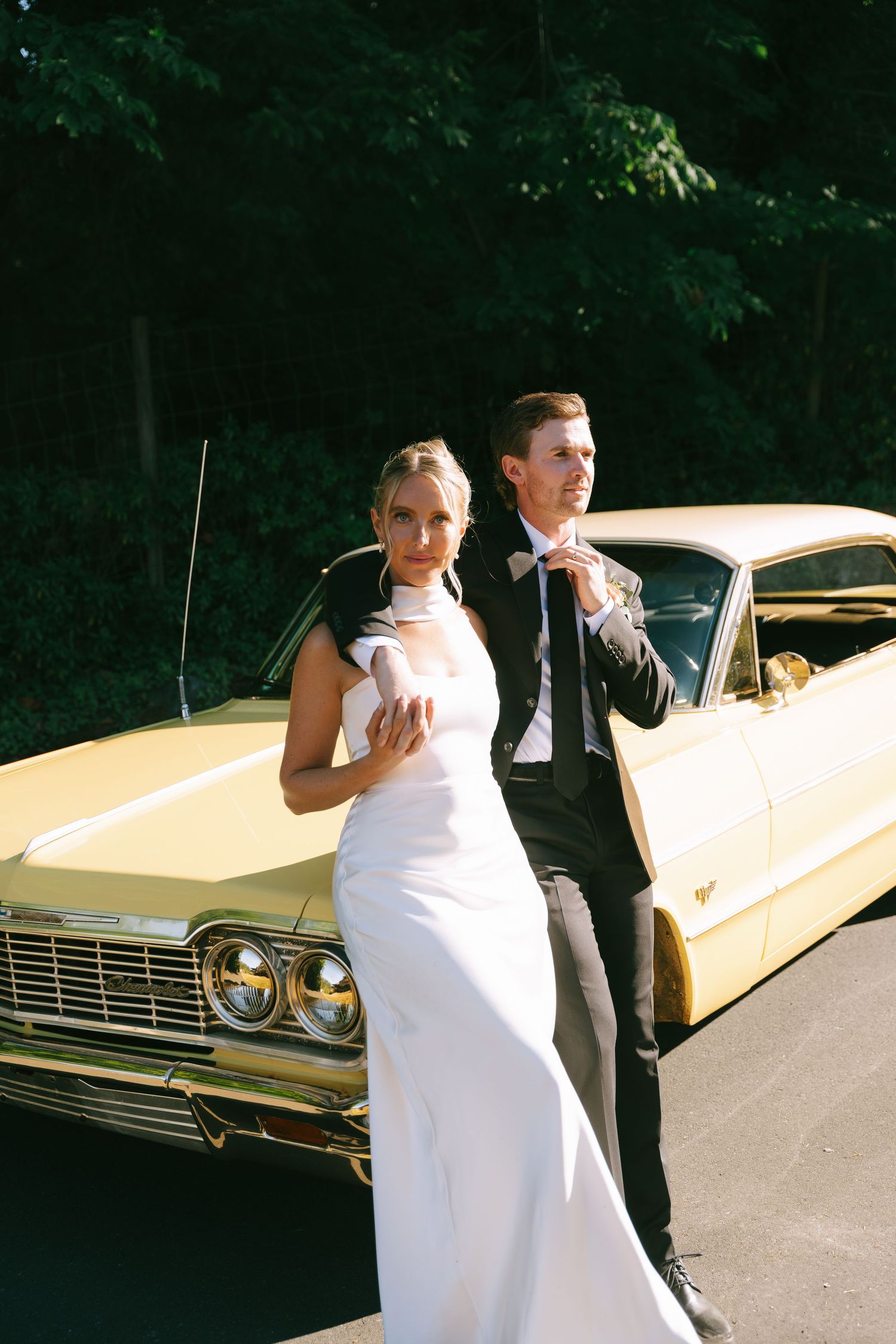 A sequence of a couple dancing outdoors in formal attire next to a vintage yellow Cadillac.