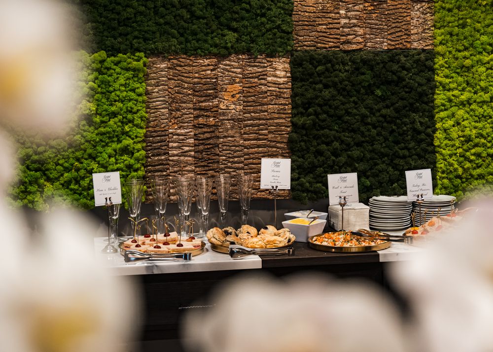 Elegant buffet table with food and wine glasses against a decorative moss and stone wall backdrop.