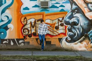 Relaxed senior portrait against urban art wall.