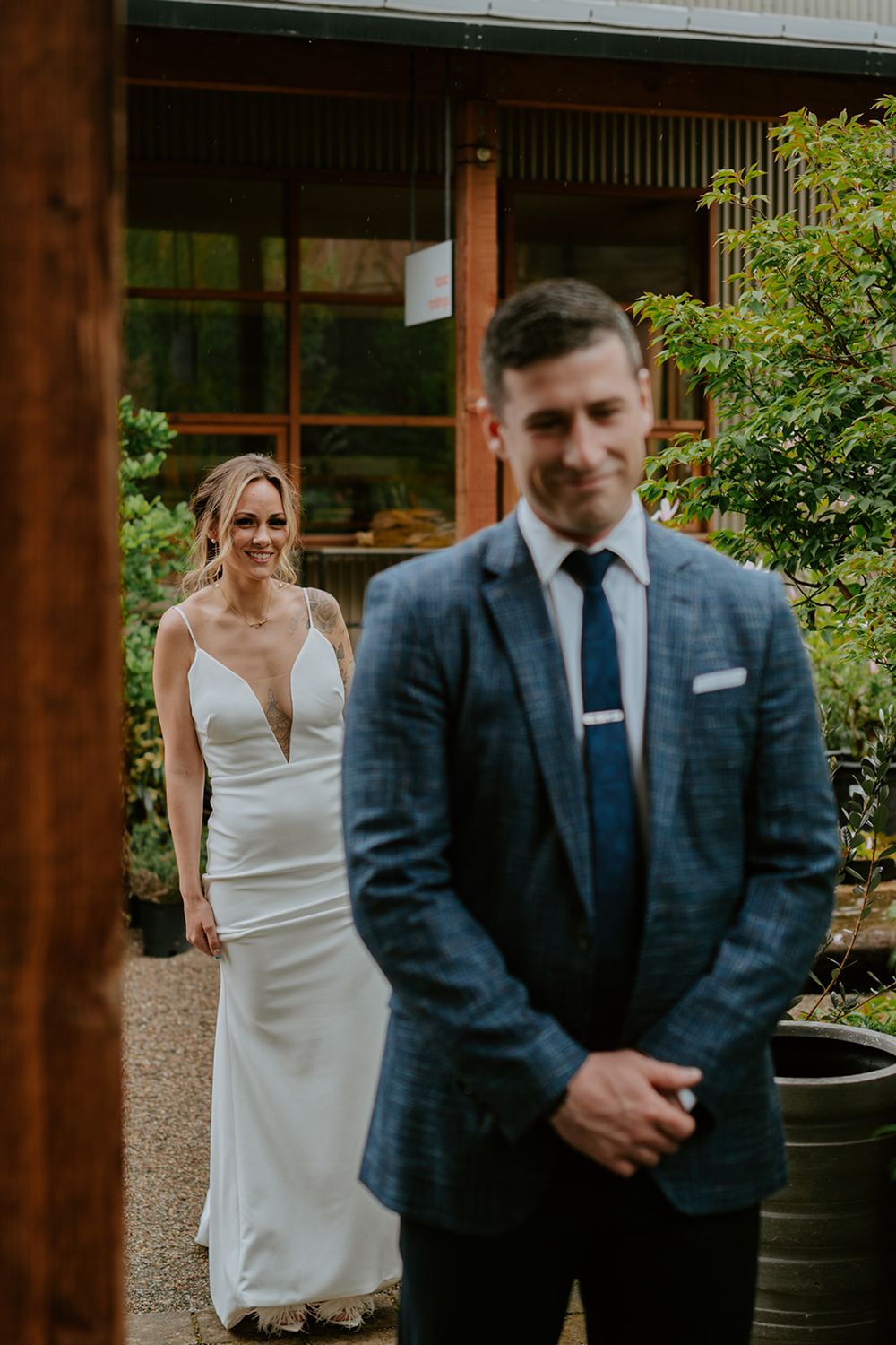 First look wedding moment captured in front of wooden building with couple in formal attire.