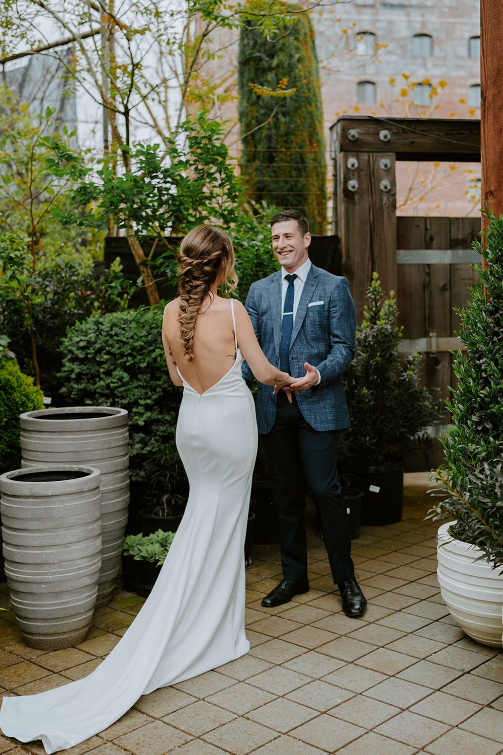 Garden wedding ceremony with couple standing on tiled patio surrounded by modern planters.